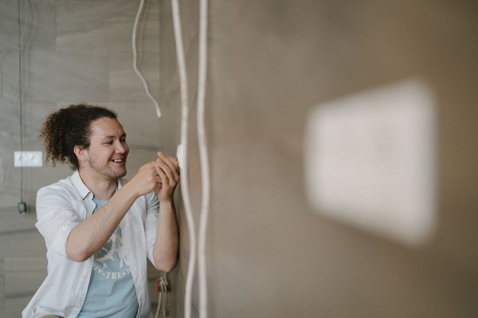 Instalador pasando cable eléctrico por una pared junto a una caja de mecanismo