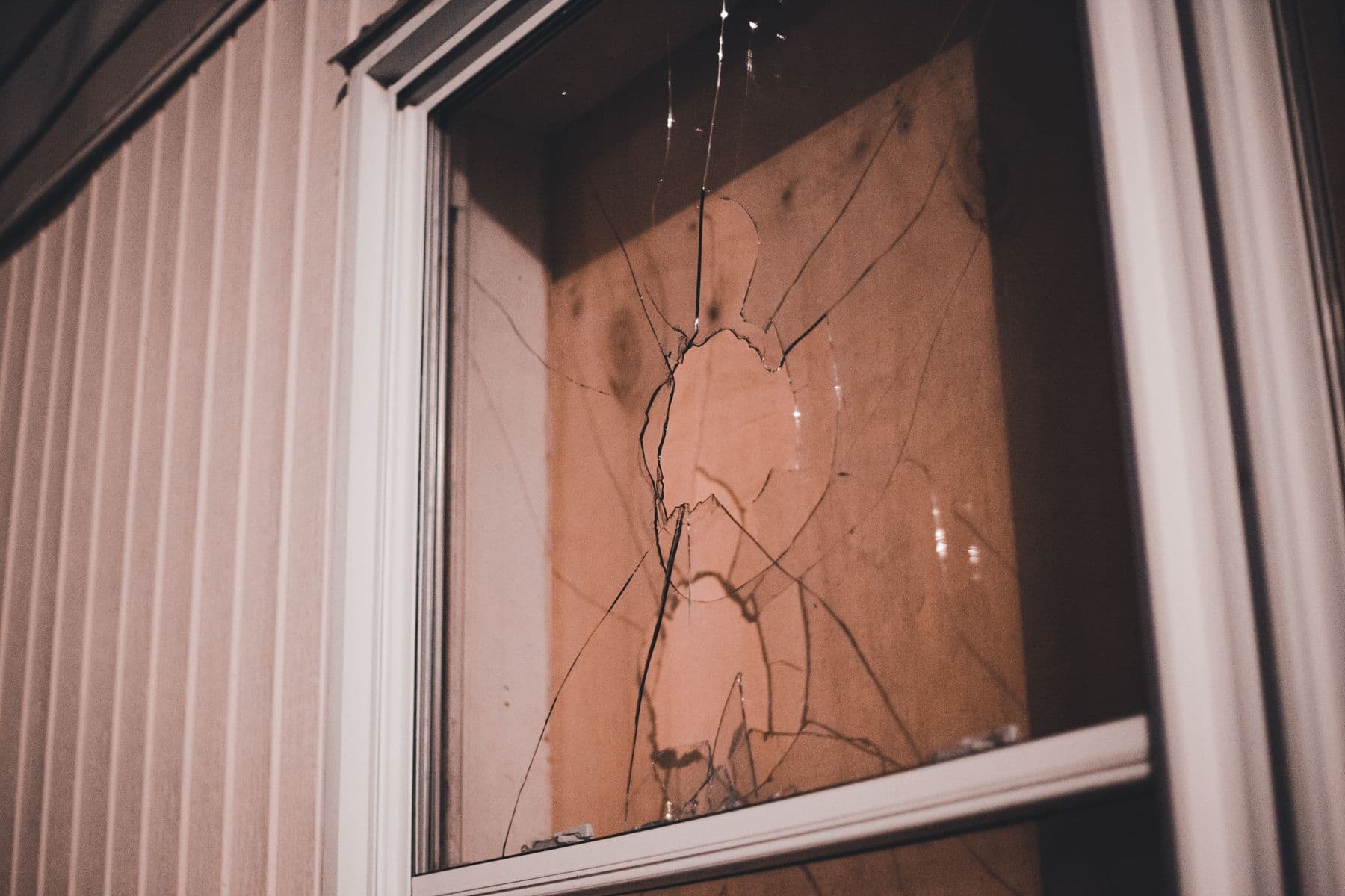 Cristal de ventana roto con grietas que salen de un impacto central