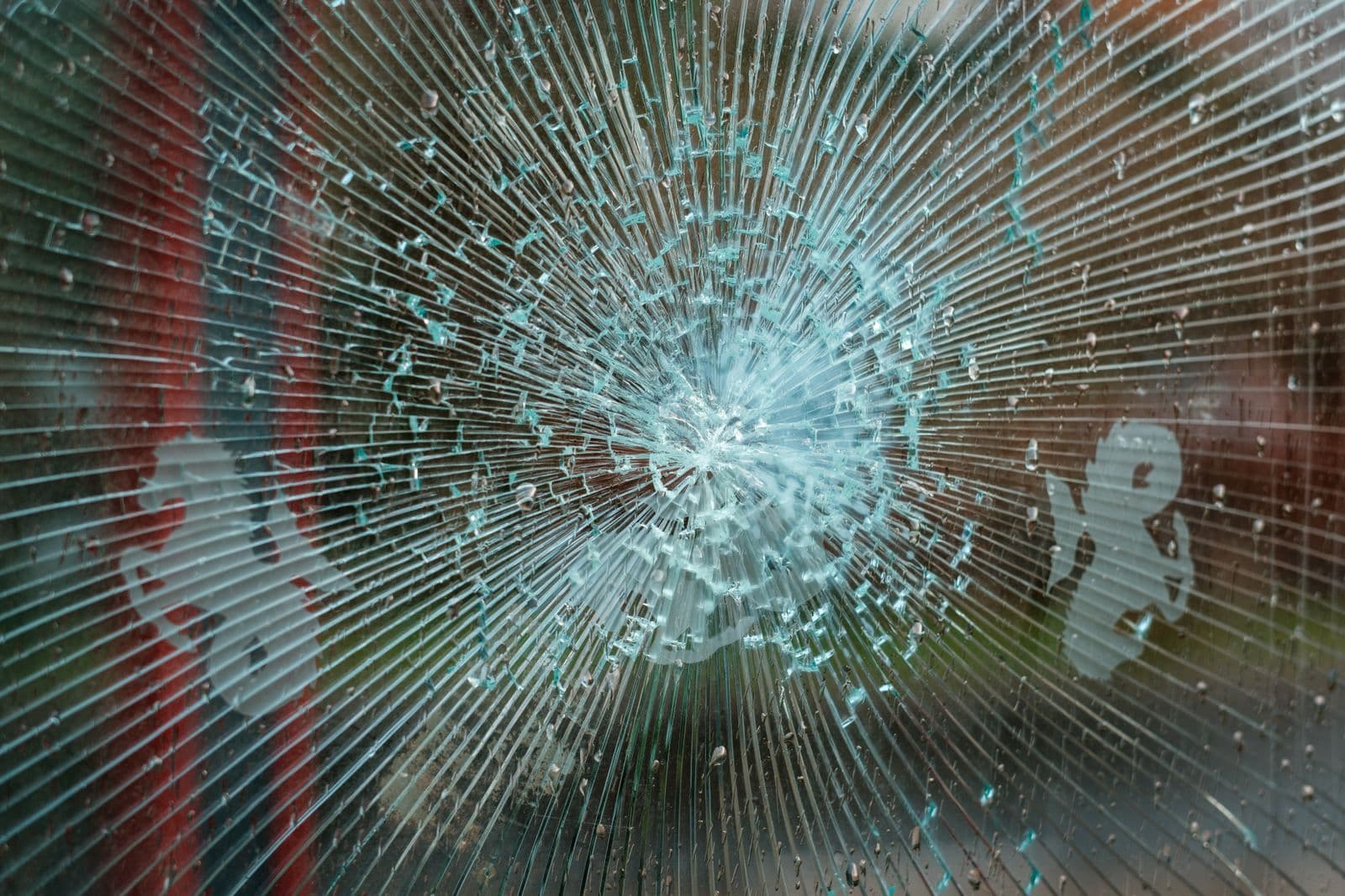 Vidrio con un impacto en forma de estrella cuyos fragmentos siguen unidos en su sitio
