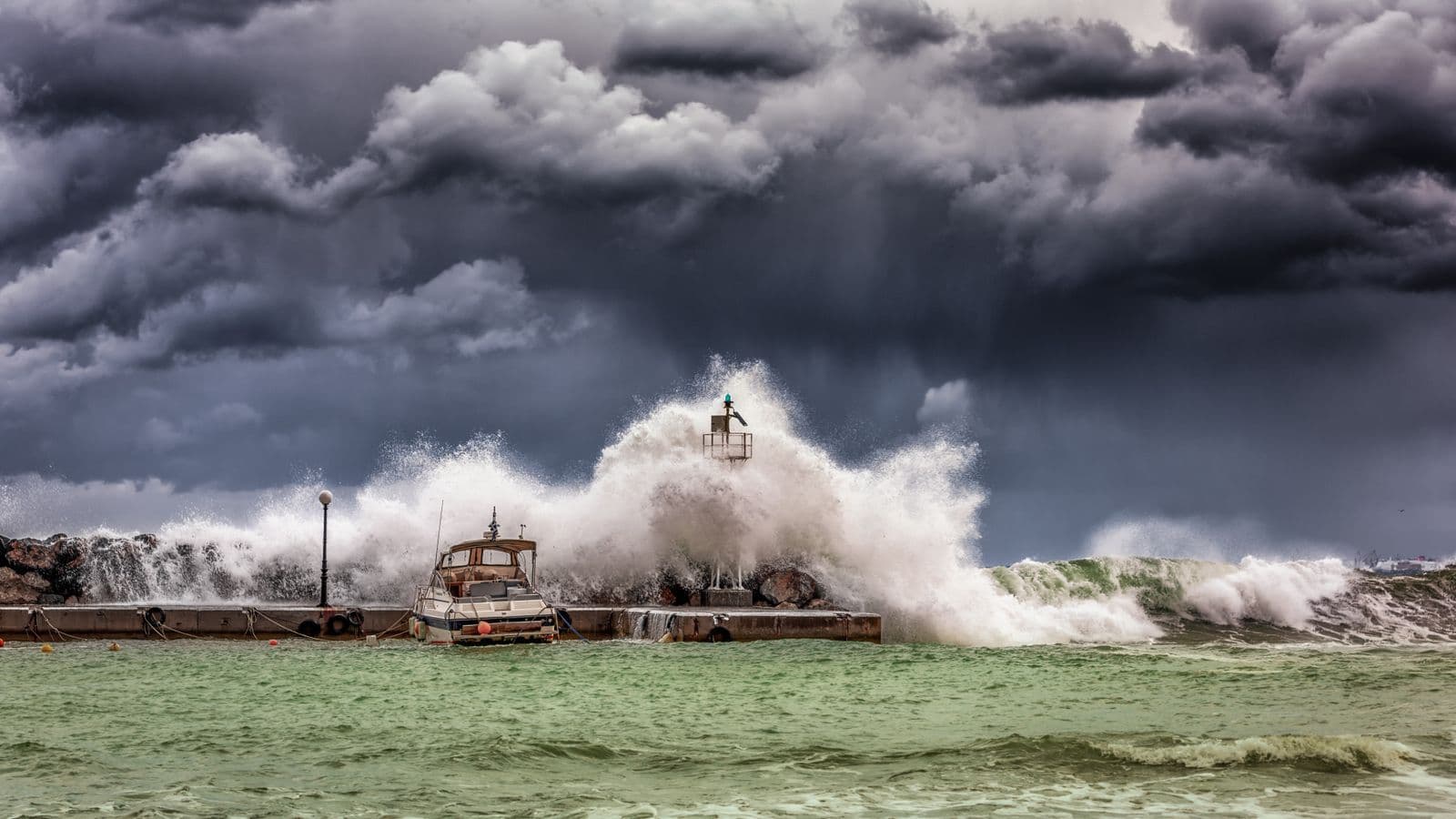 Olas rompiendo contra un espigón bajo un cielo de tormenta