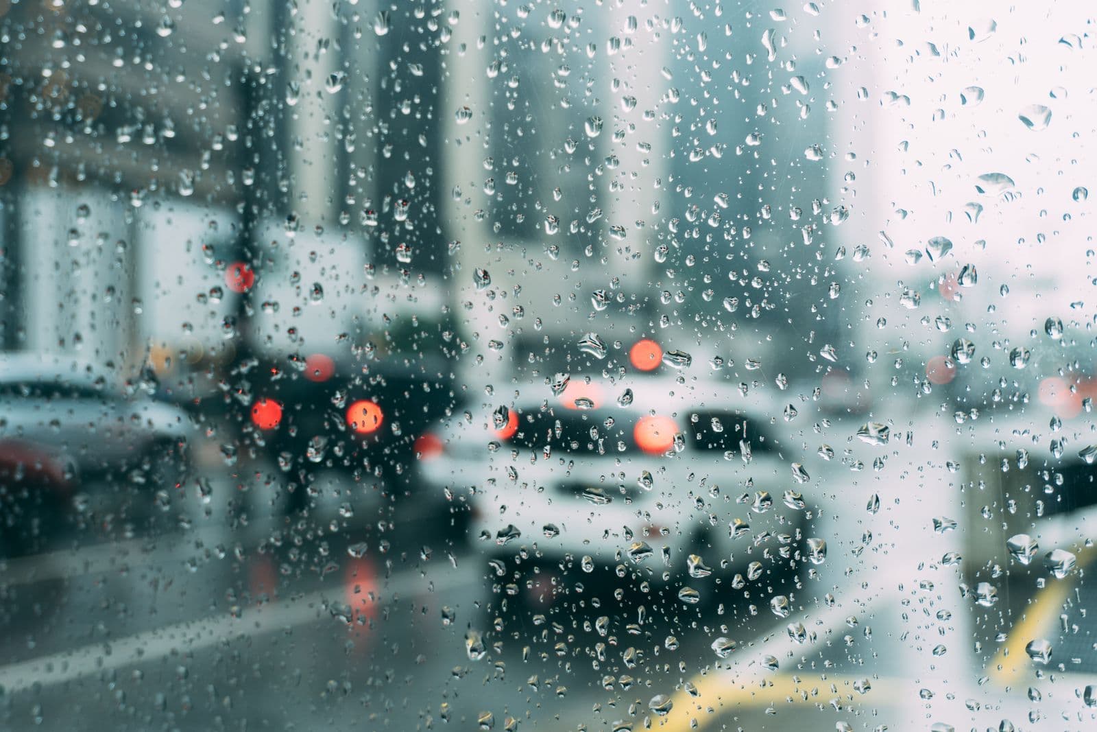 Tráfico de una calle desenfocado tras un cristal con gotas de lluvia
