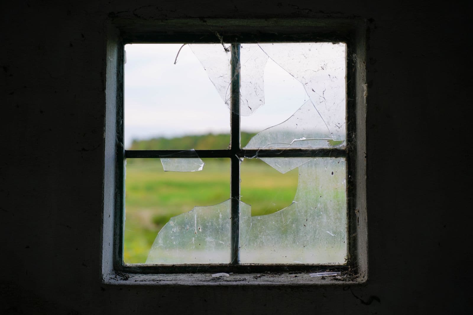 Ventana de cuarterones con un cristal roto y trozos sueltos en el marco